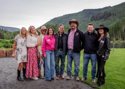 Eight Gunnison Tough Board Members line up for a picture at the Songwriter Soiree amid a mountain backdrop.