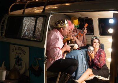 A group of friends wearing silly hats posing in the photo bus.