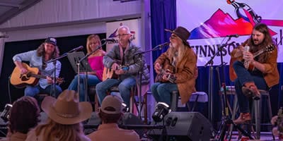 July 2024 signer Songwriters performing amid purple and pink lights and a large crowd.