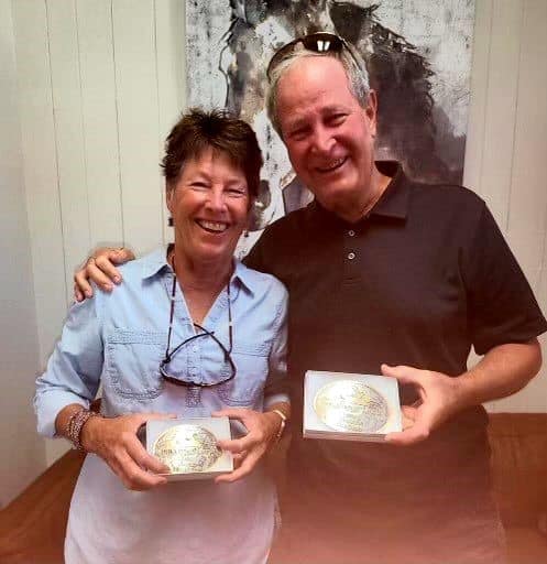 2024 Survivor Buckle winners, Jim Swain and Missy Kizer, smile and hold out their buckles.