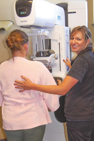 A patient and technician at a breast screening exam.