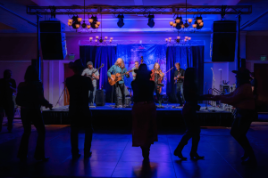 Wood Box Heroes perform while dancers on the floor in silhouette.